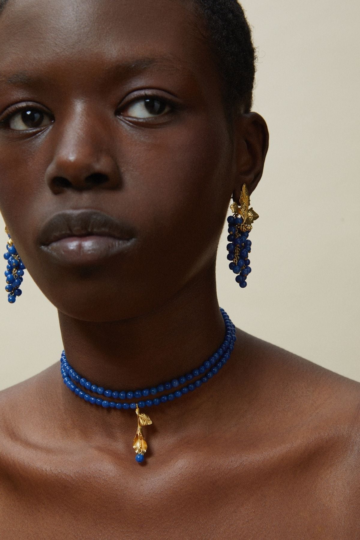 Woman wearing blue jewelry with gold accents against a neutral background
