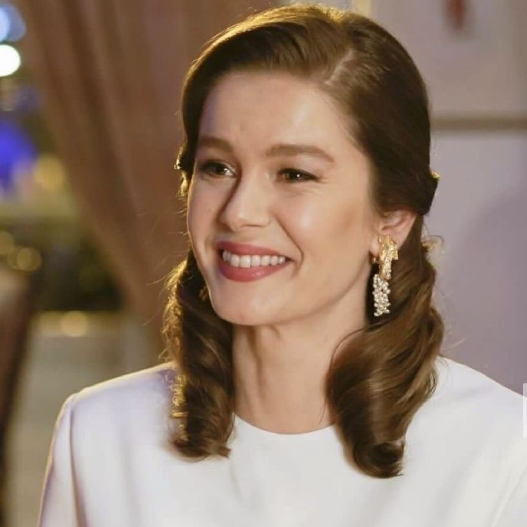 Woman with styled hair and earrings in a blurred indoor setting