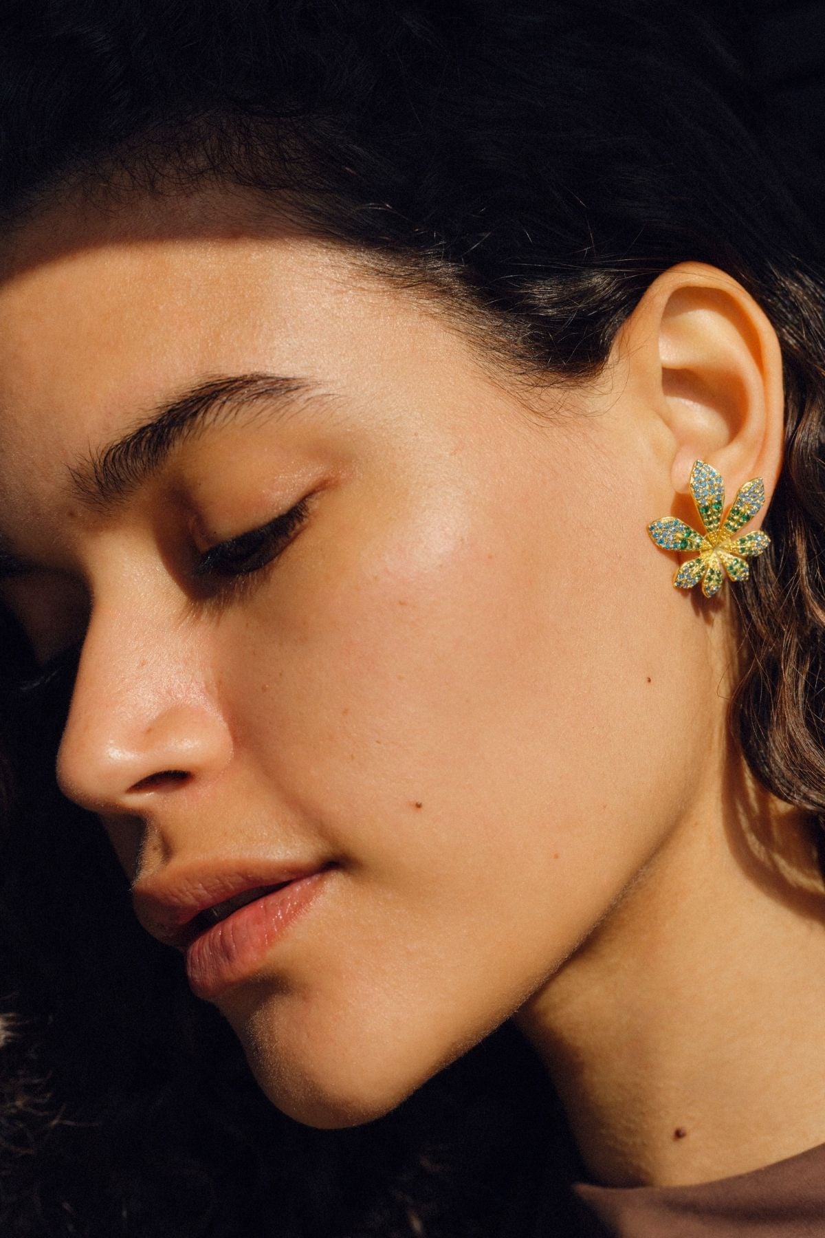 Close-up of a person wearing a decorative earring with a dark background