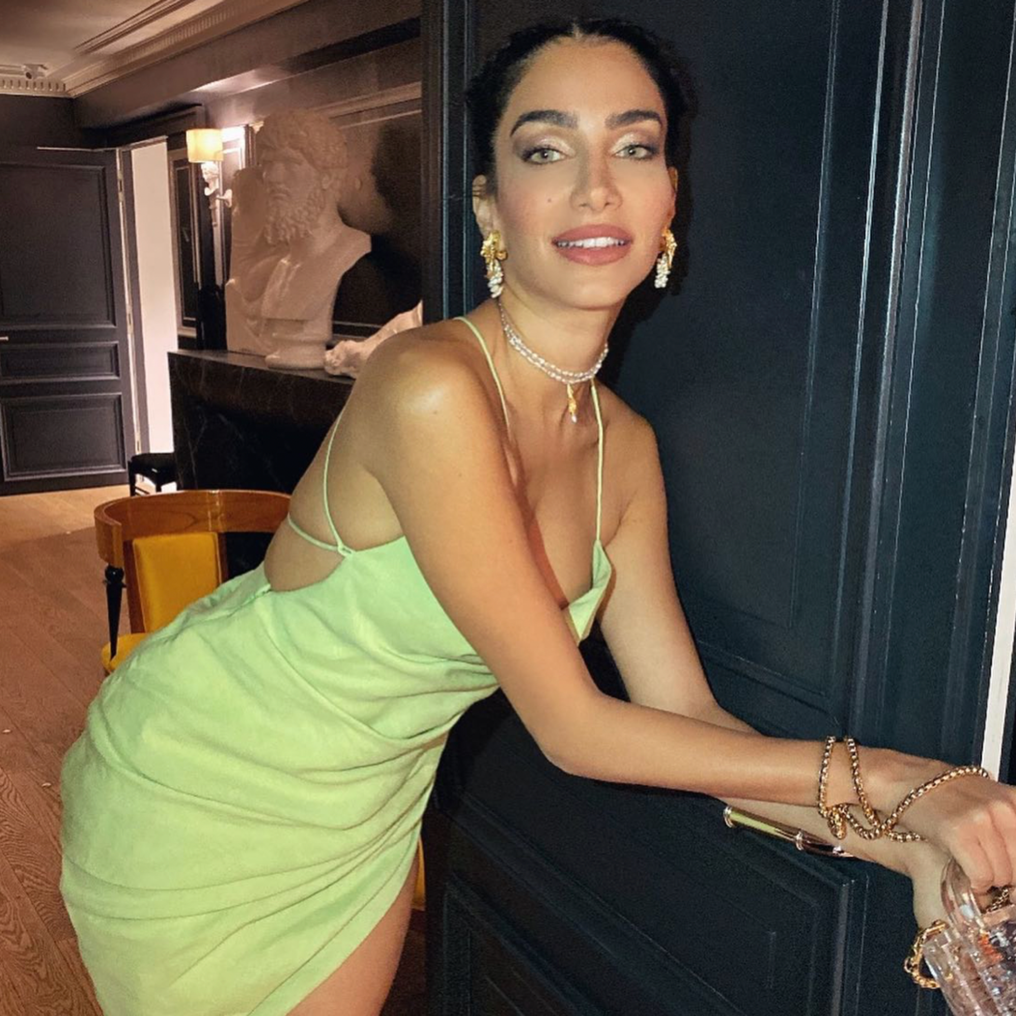 Woman in a green dress sitting indoors with a dark background