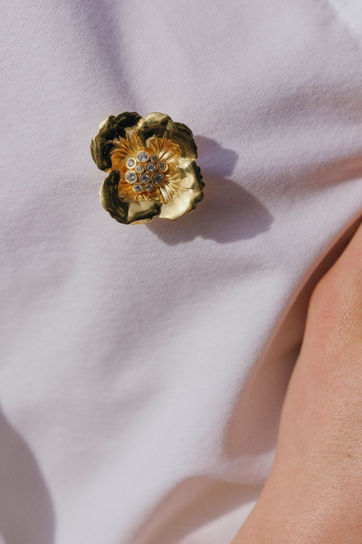 Gold flower-shaped brooch on a white fabric background